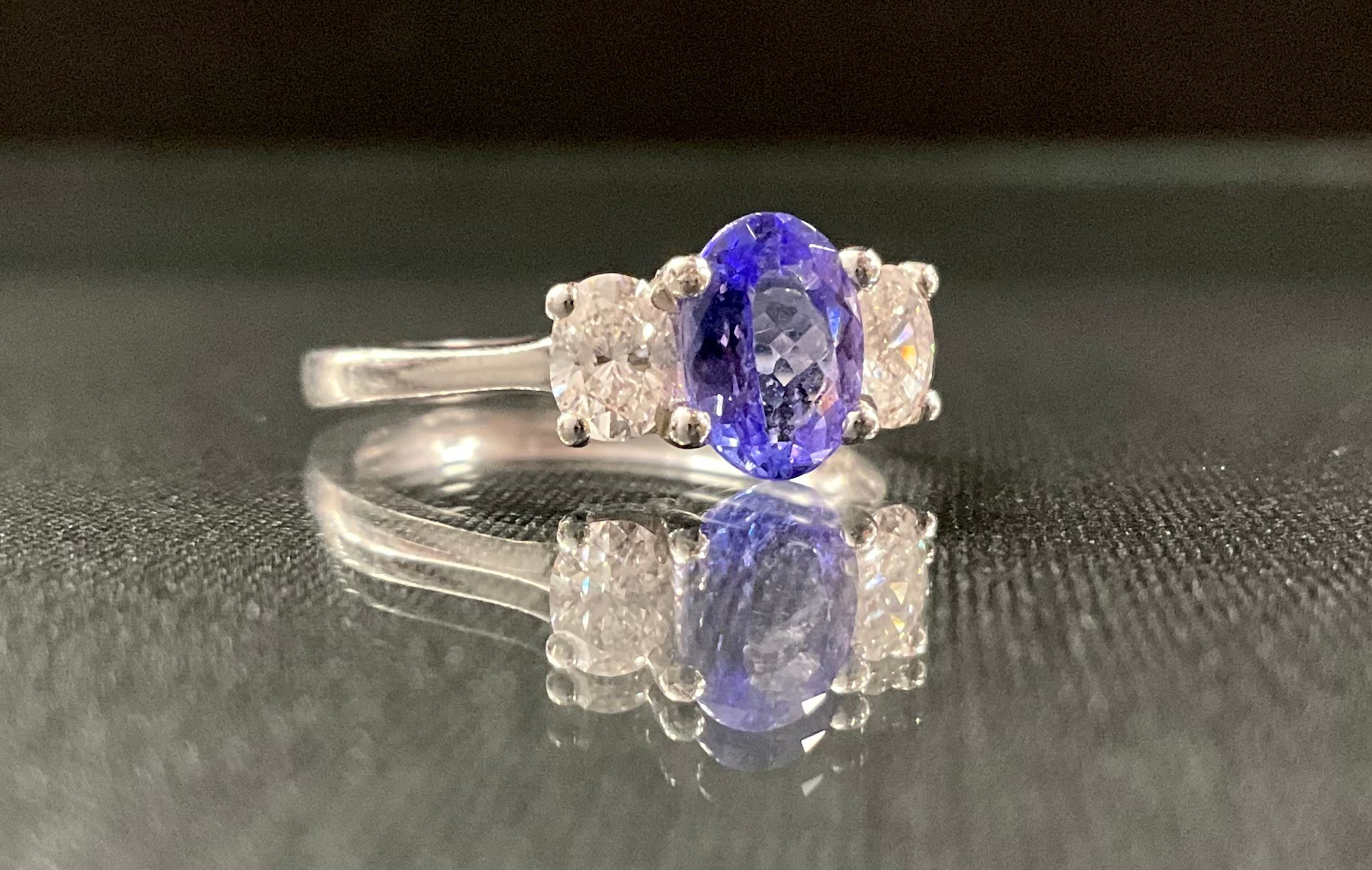 A tanzanite and diamond ring, central oval tanzanite approx 1.06ct, between oval cut diamonds, total