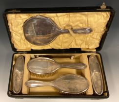 A George V silver dressing table set, comprising hand mirror, a pair of hair bushes, a pair of