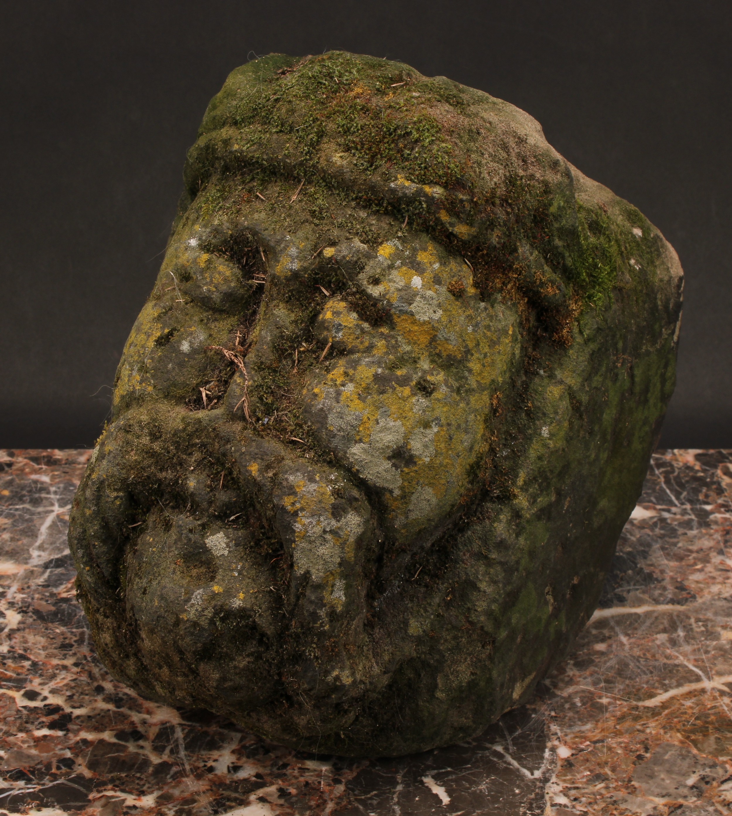 A Medieval gritstone corbel, carved as the head of an ecclesiastical dignitary, 26cm high, 14th/15th