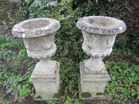 Pair of concrete garden urns on plinths (slight damage to corner of one urn base as shown in