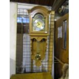 A German Interlock wall hung  long cased clock with oak case, brass weights and key, plus manual