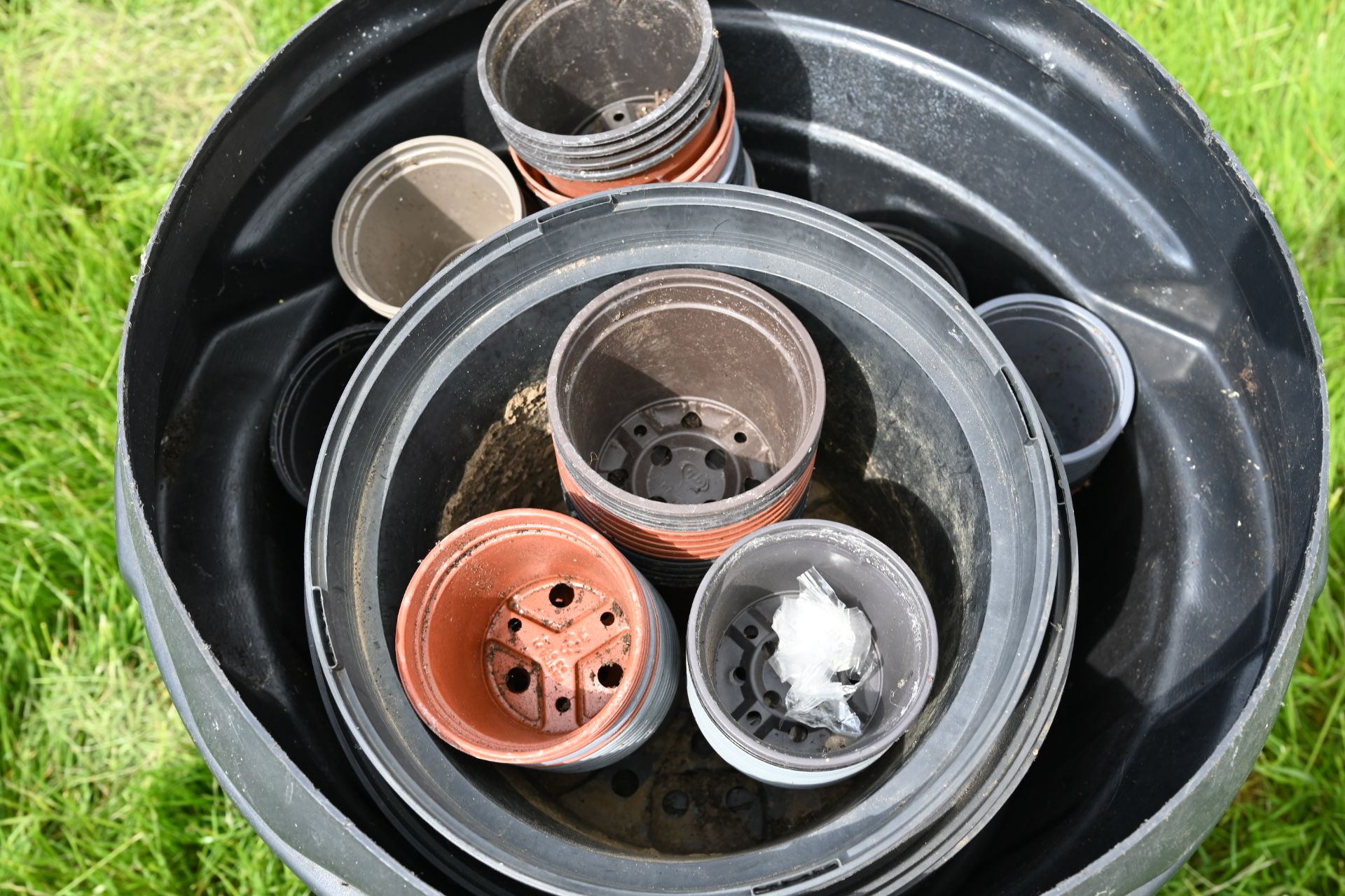 Plasic dustbin full of garden pots