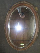 A oval carved framed bevelled mirror