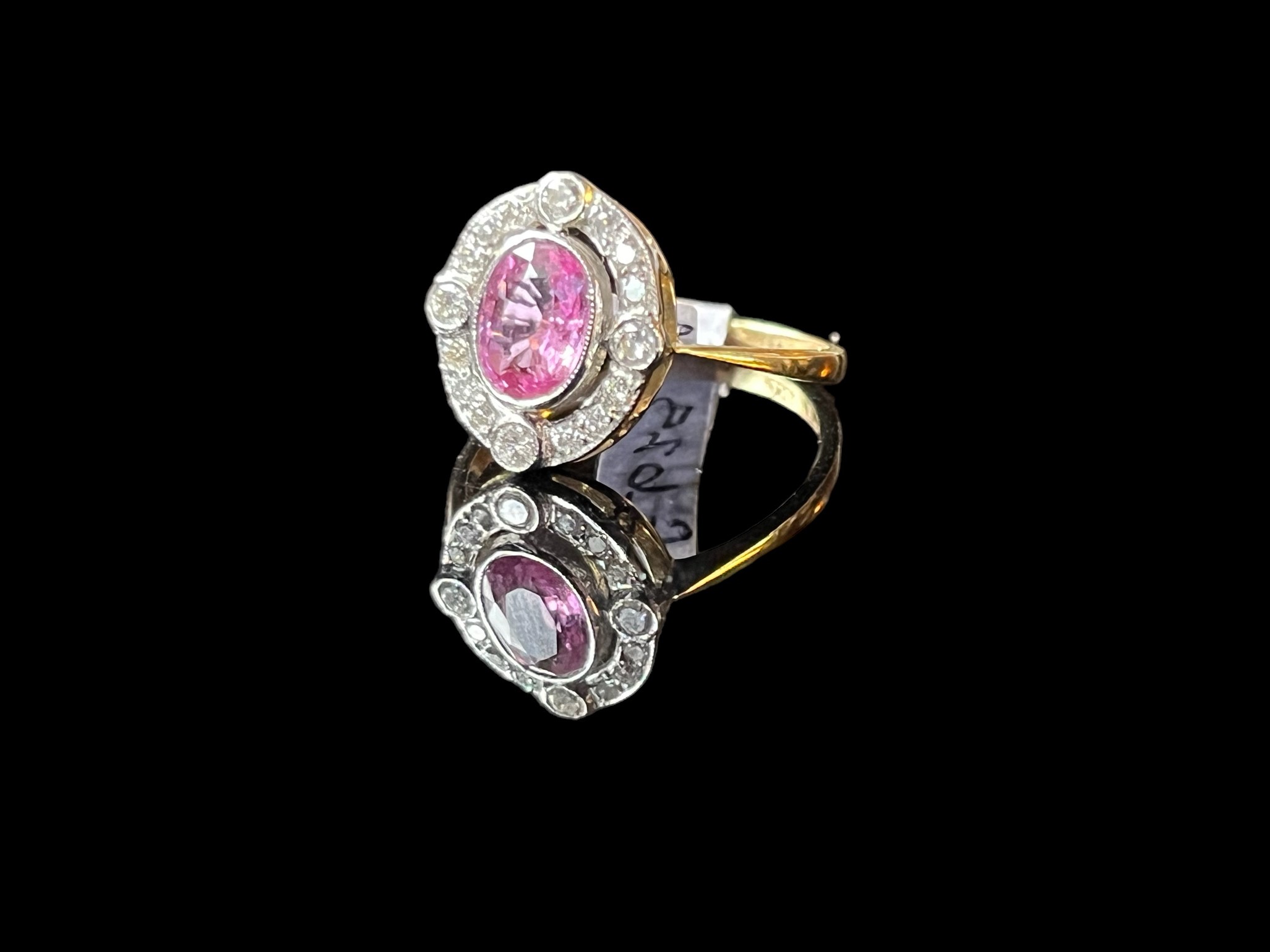 A pink sapphire and diamond ring, set with an oval pink sapphire weighing 0.60 carats, within a