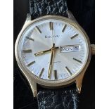 9ct gold gents wrist watch by Bulova having a baton numeral dial with day & date aperture, leather