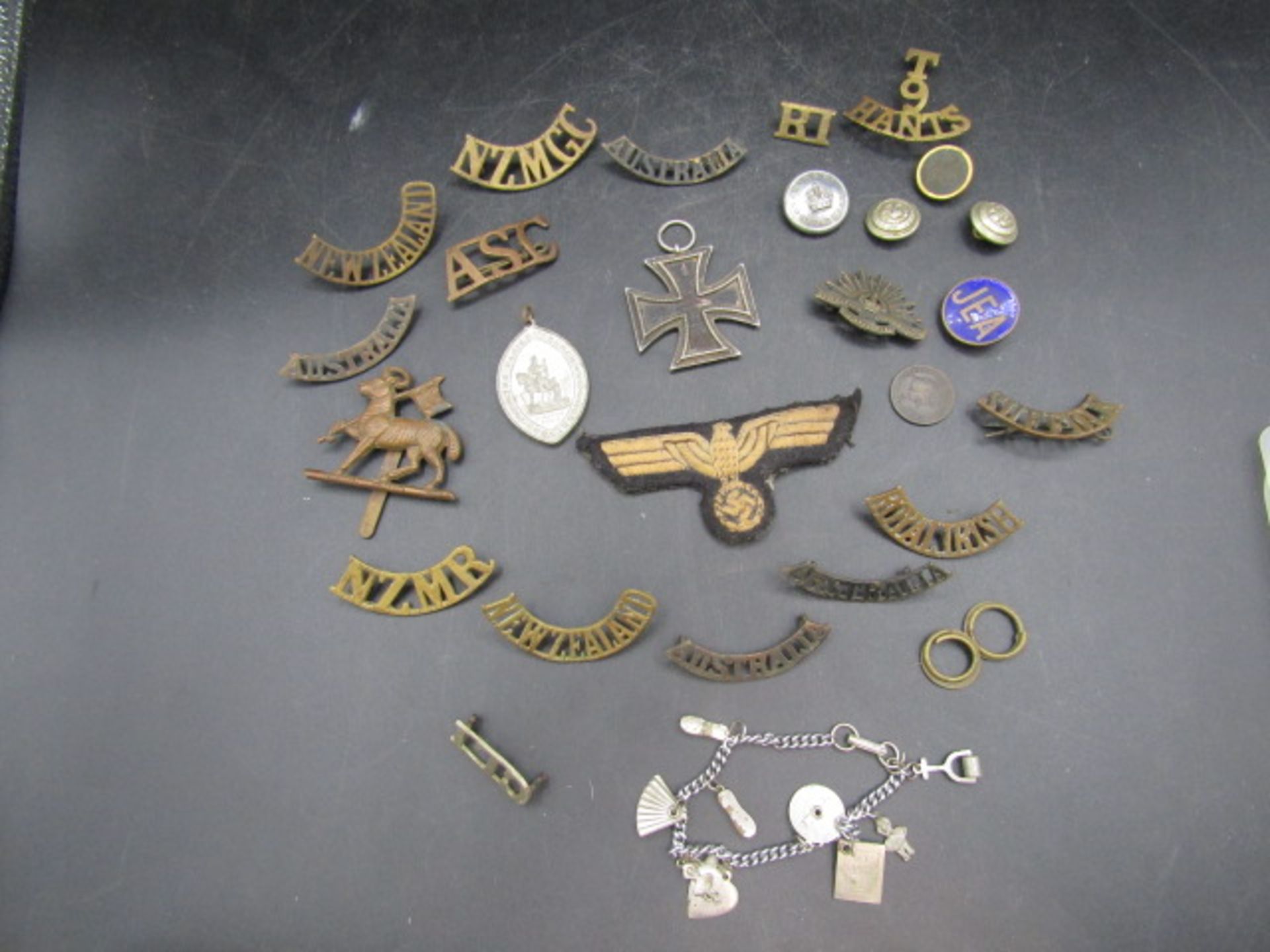 WW2 iron cross and various insignia badges and patches plus a charm bracelet