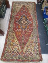 a vintage Eastern red ground rug 210x90cm