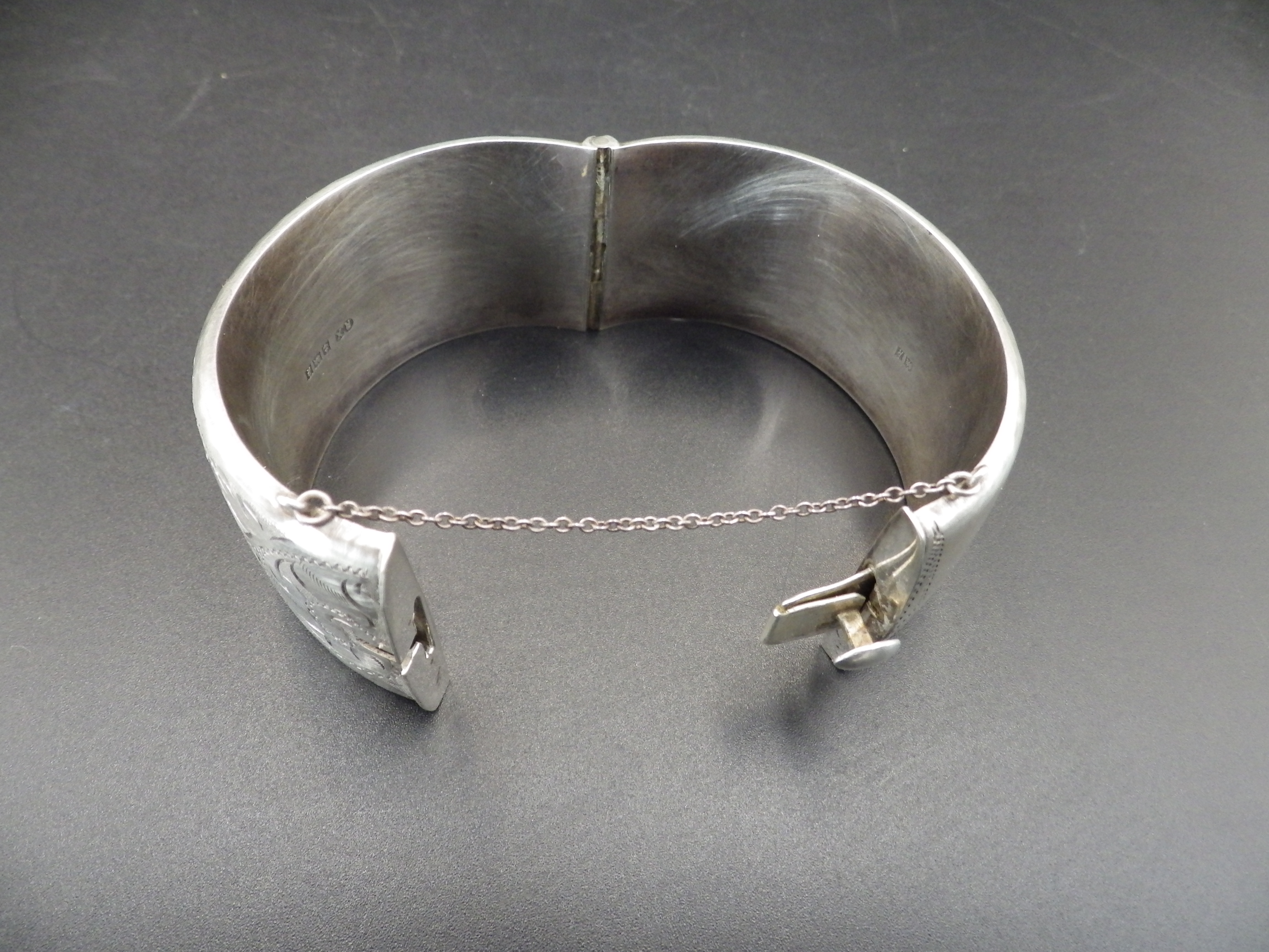 A silver hallmarked hinged bangle with safety chain (Birmingham 1966 by Ronex) 49.18g total weight. - Image 2 of 4