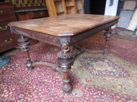 A heavily carved table with lion face details to corners 132x99cm 74cmH 2 rings missing from lion'