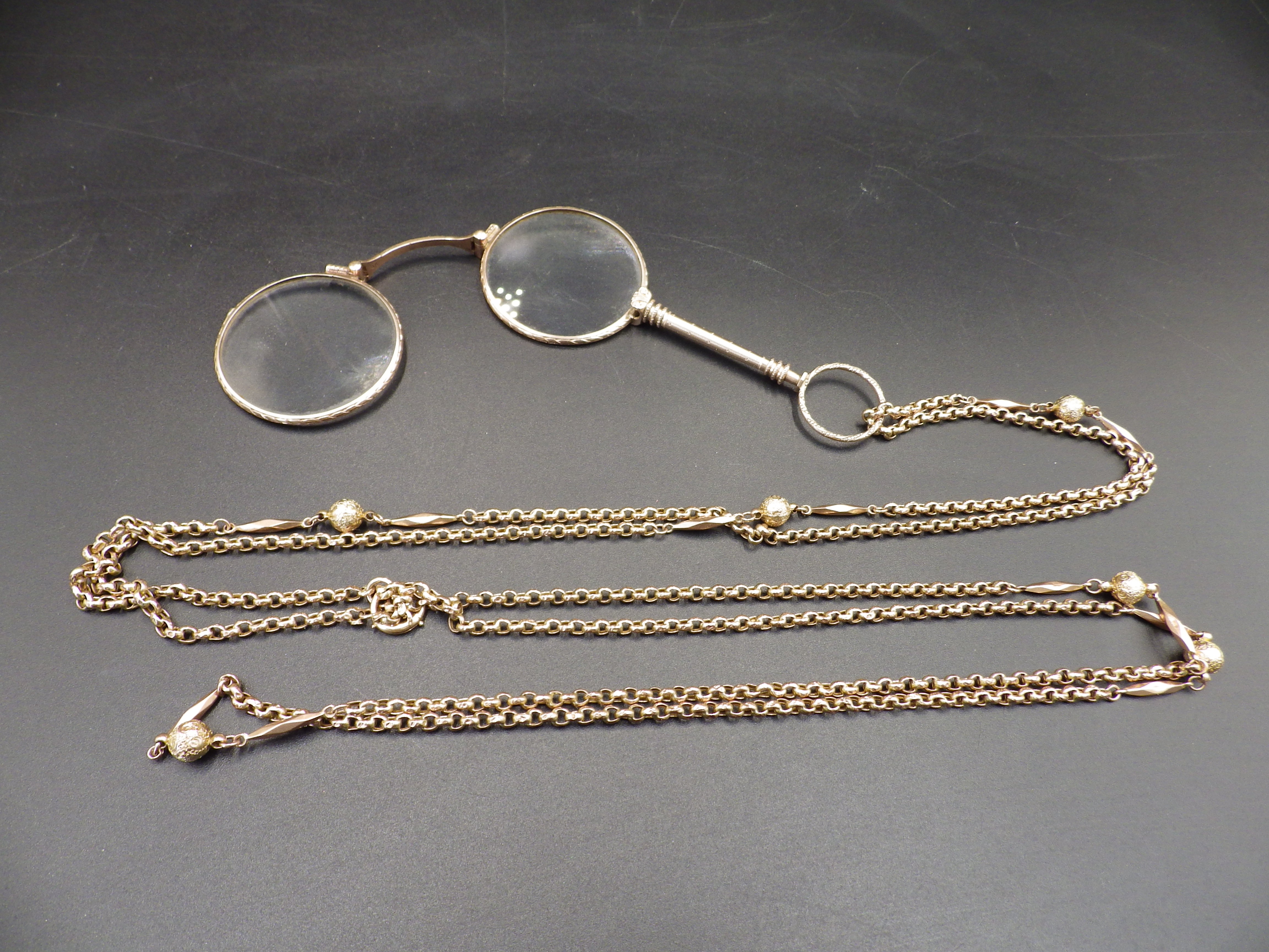 A double lorgnette marked 9 kt, on a gold chain marked 9 ct with decorative sphere detail, the chain