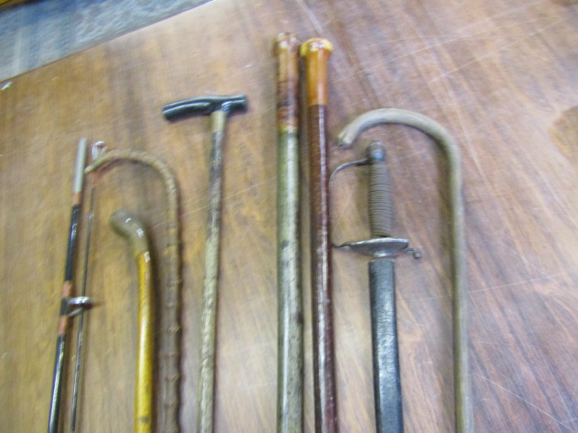 Various walking canes/sticks, a sword and a fishing rod