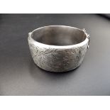 A silver hallmarked hinged bangle with safety chain (Birmingham 1966 by Ronex) 49.18g total weight.