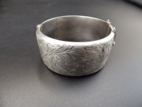 A silver hallmarked hinged bangle with safety chain (Birmingham 1966 by Ronex) 49.18g total weight.