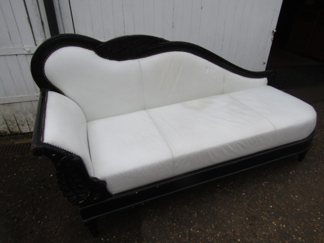 A chaise longue with white leather/ette upholstery on a black frame