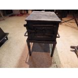 Large cast iron stove with grate and latch door on stand, stove is 34cm x 25cmx 19cm tall