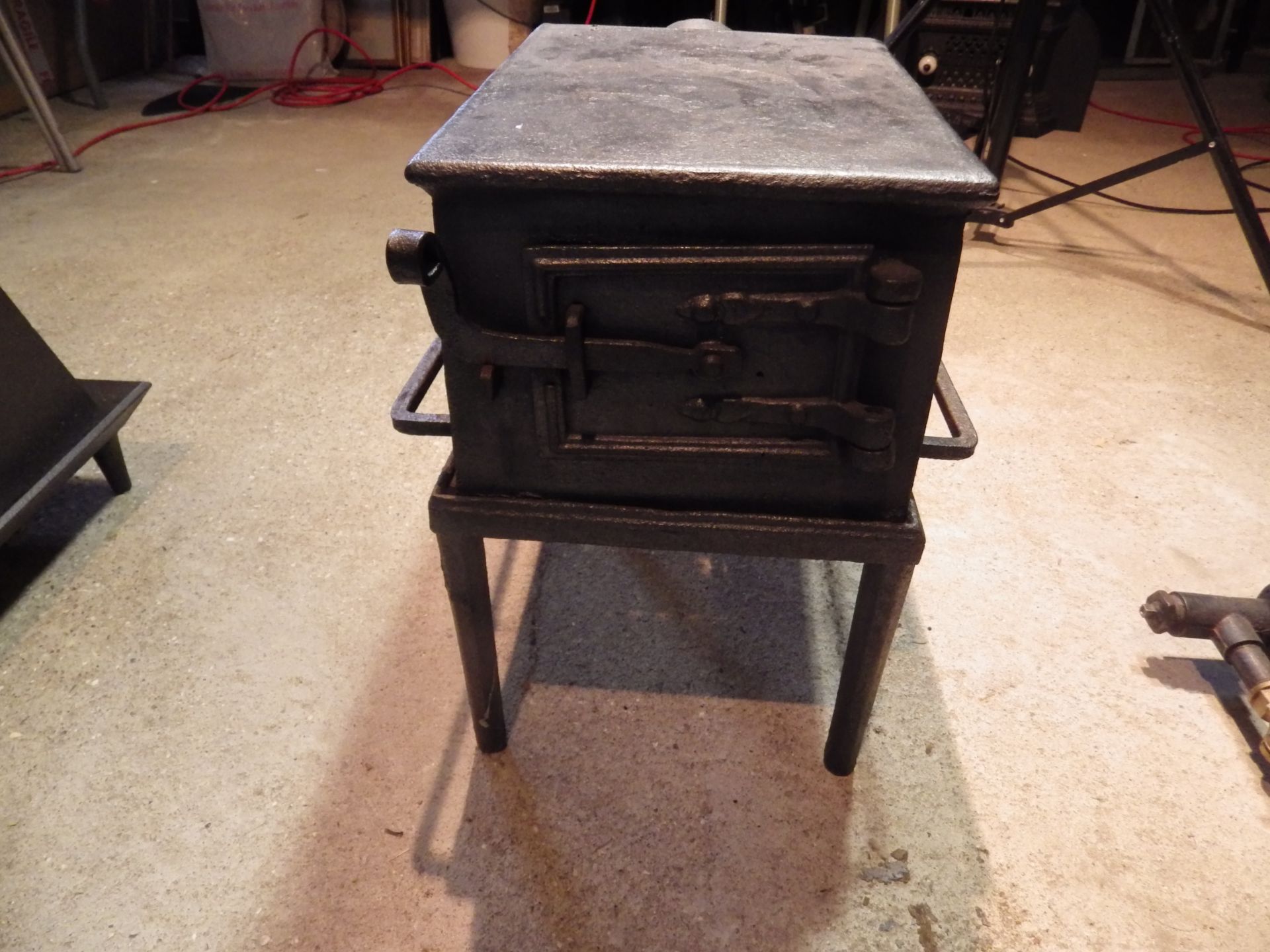 Large cast iron stove with grate and latch door on stand, stove is 34cm x 25cmx 19cm tall