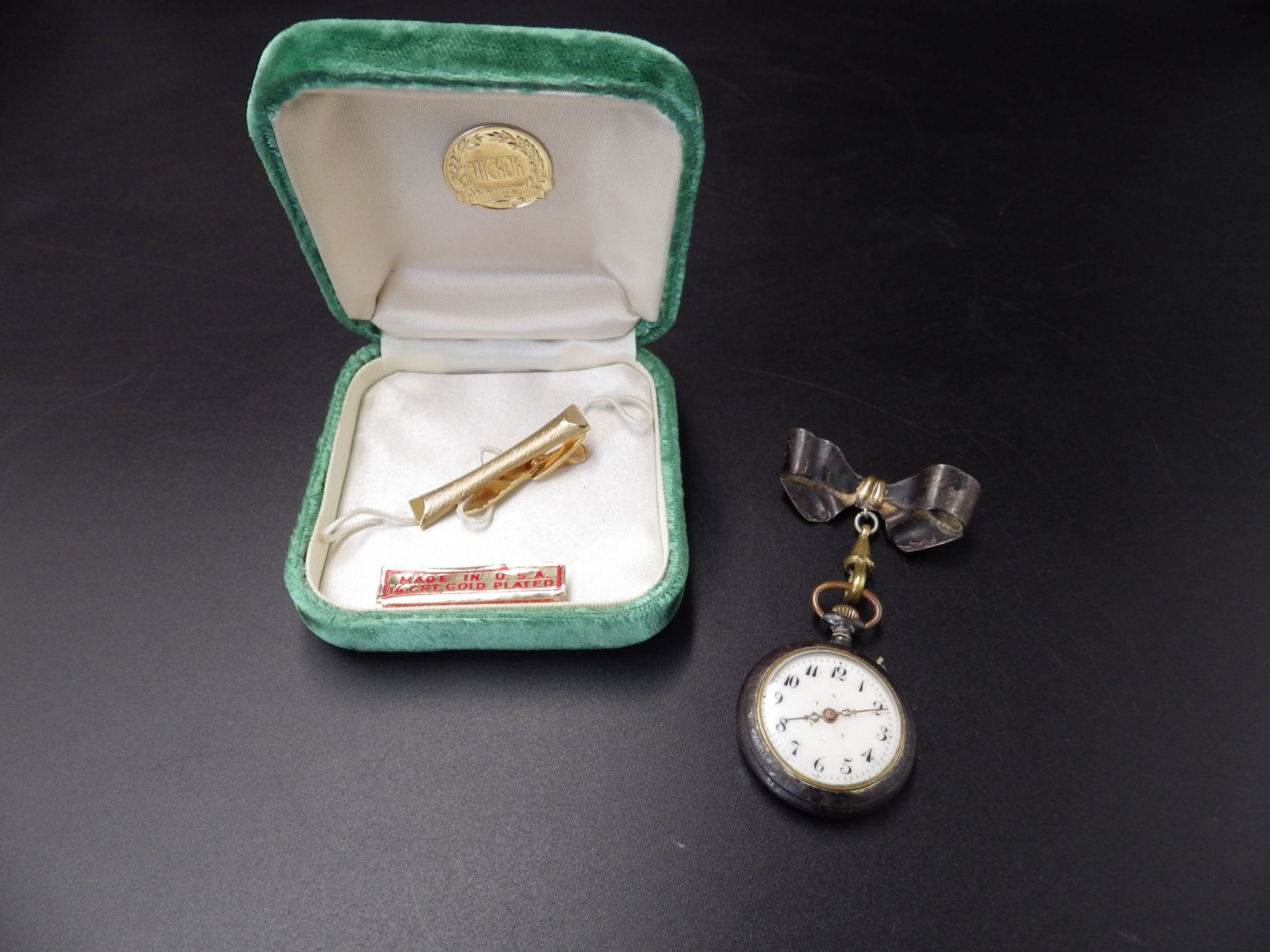 An early 20th C ladies lapel watch in a 'gun metal' case, with a bow pin fastening, and a 14ct