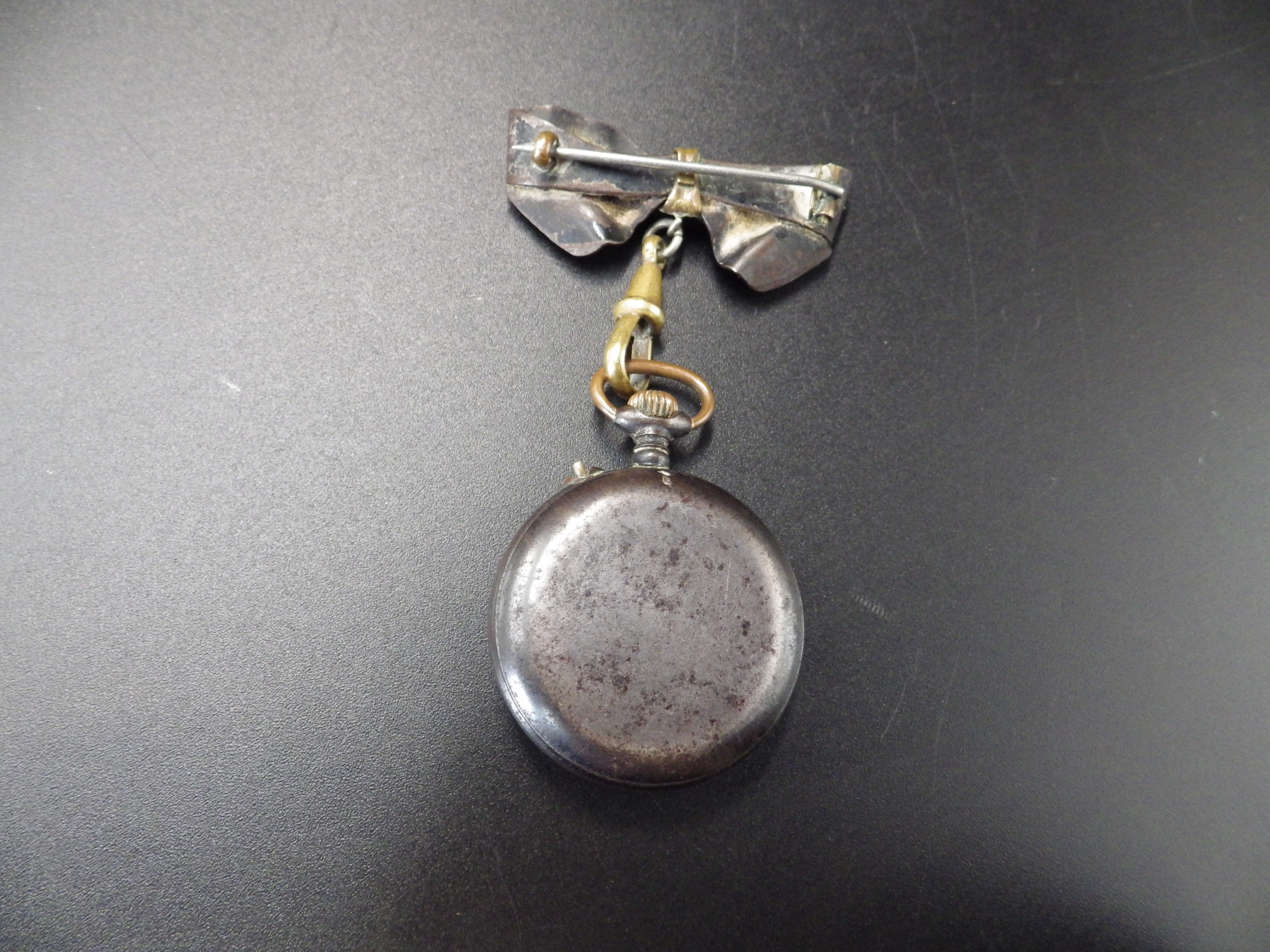 An early 20th C ladies lapel watch in a 'gun metal' case, with a bow pin fastening, and a 14ct - Image 4 of 4