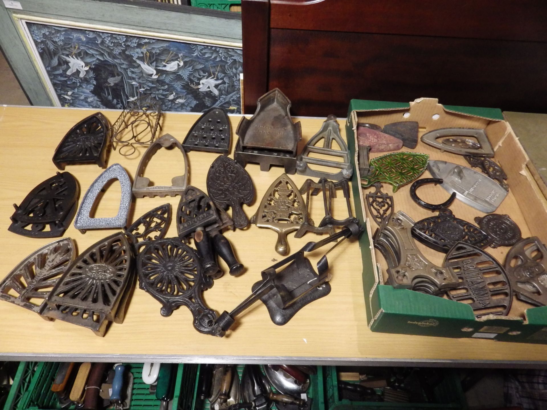 Tray of assorted iron trivets in various materials, slugs etc to include a french iron stand and