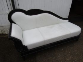 A chaise longue with white leather/ette upholstery on a black frame