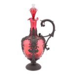 A cranberry glass claret jug and stopper with embossed pewter mounts and handle, 34cm high overall.