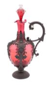 A cranberry glass claret jug and stopper with embossed pewter mounts and handle, 34cm high overall.
