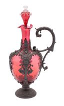 A cranberry glass claret jug and stopper with embossed pewter mounts and handle, 34cm high overall.