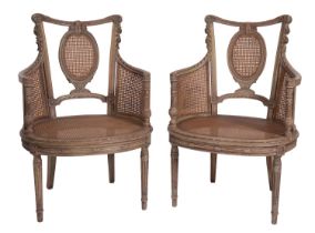 A pair of carved and painted wood and canework bergere elbow chairs in Louis XVI taste,