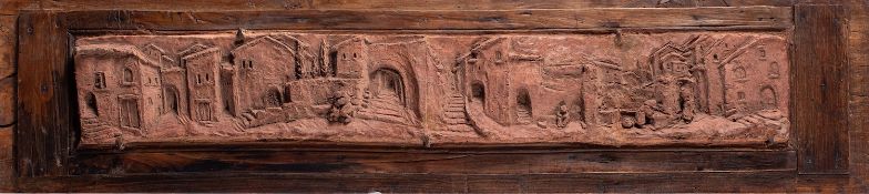 A Italian terracotta plaque, decorated in deep relief with a panoramic view of a village,