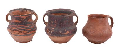 A group of three Chinese Neolithic terracotta jars two with black painted geometric decoration,