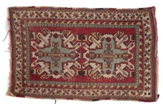 A Kurdish rug, the brick red field with ivory and pastel geometric medallions,