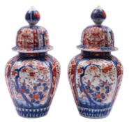 A pair of Japanese Imari vases and domed covers, of ribbed oviform,