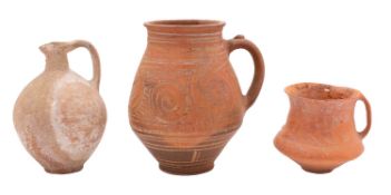 A Greek terracotta jug painted with scrolling motifs between line borders, 20cm; a similar cup,