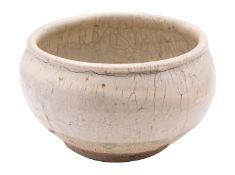 A Chinese cream glazed bowl with rolled rim, the thick glaze falling short of the foot,