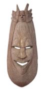 An African carved hardwood mask, 20th century; the elongated, oval visage with stylised features,