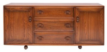 An Ercol stained elm sideboard, circa 1970s; the front with three drawers flanked by opposing doors,