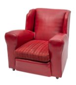 A red faux leather covered wingback armchair, circa 1920; with broad armrests and padded seat,