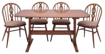 A stained elm dining table and four chairs en suite, by Ercol,