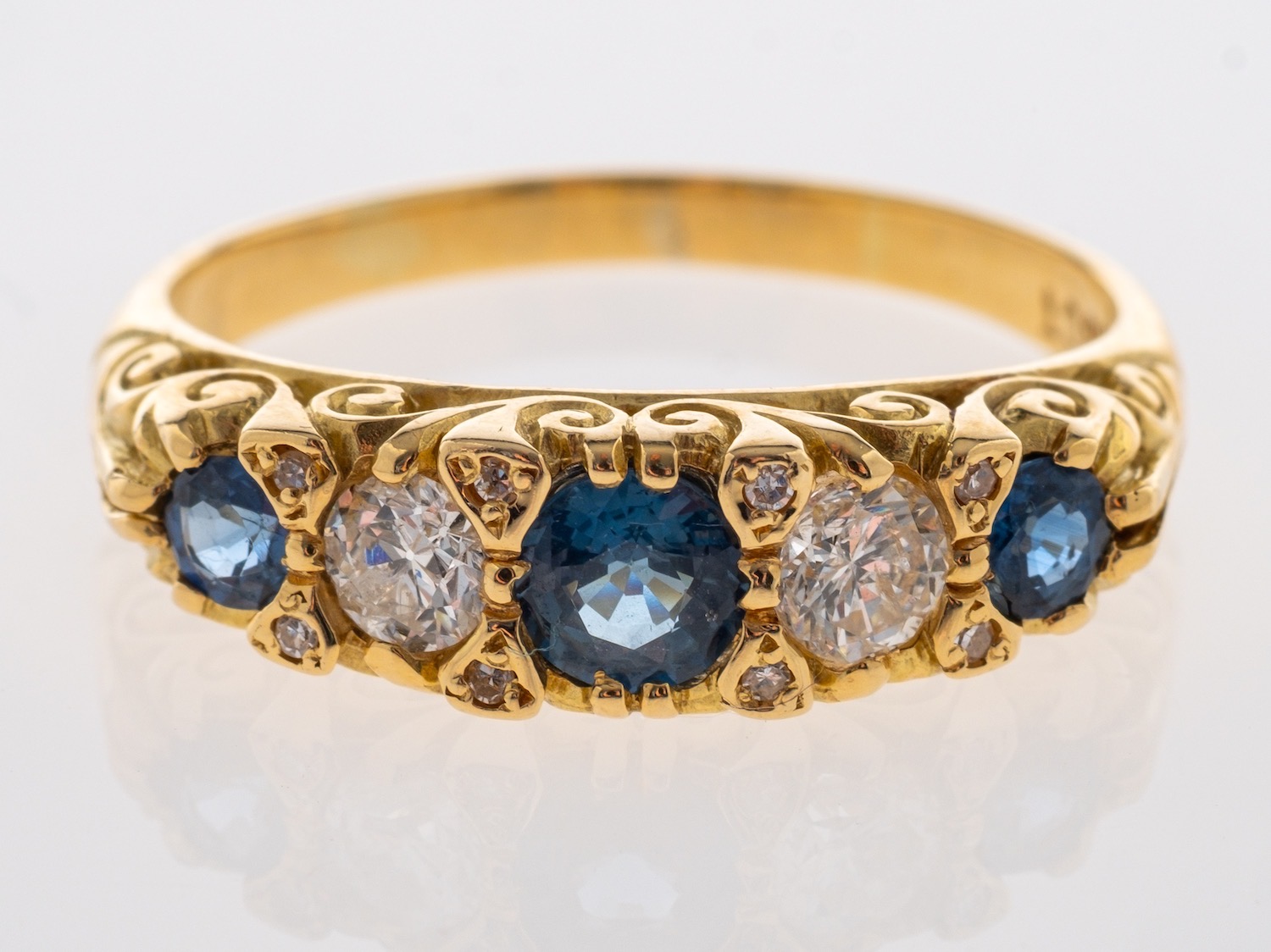 A sapphire & diamond five stone ring in carved 18ct yellow gold mount, sapphires are mid blue,