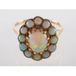 An opal ring, the central oval cabochon opal claw set within a surround of circular cabochon opals,