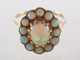 An opal ring, the central oval cabochon opal claw set within a surround of circular cabochon opals,