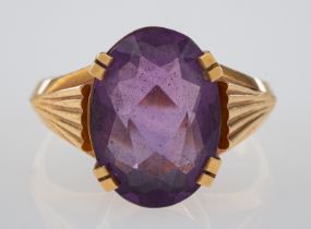 A dress ring set with an oval faceted amethyst, the shoulders cut with fan form grooves,
