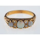 An opal and diamond ring, the three circular cabochon opals with eight cut diamonds in between,