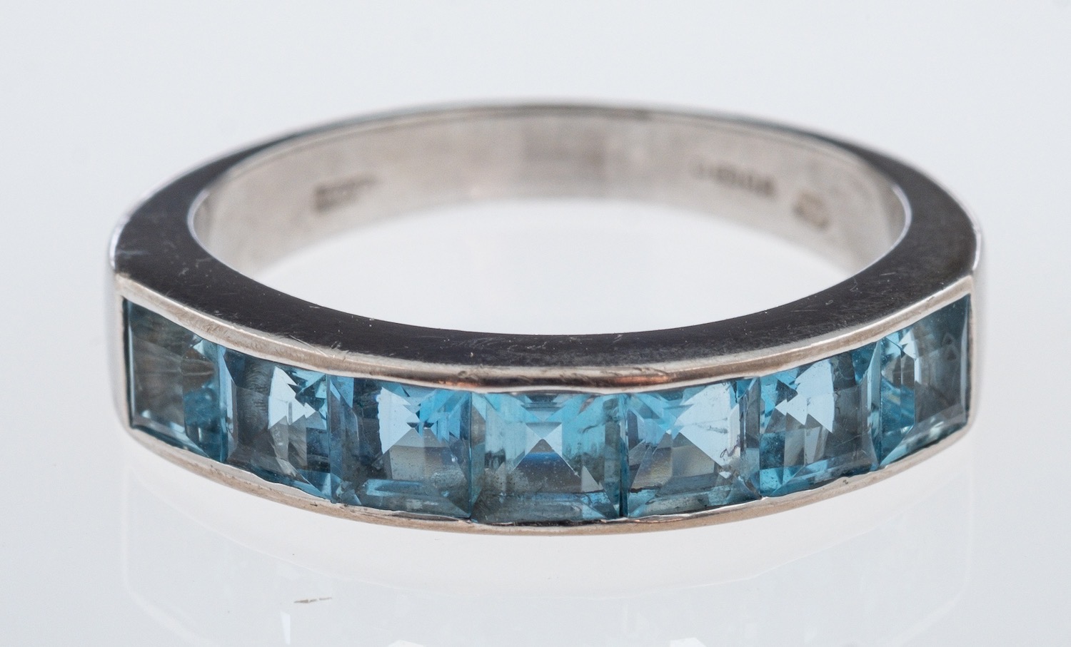 A modern aquamarine set ring, the square cut stones channel set in 18ct white gold,