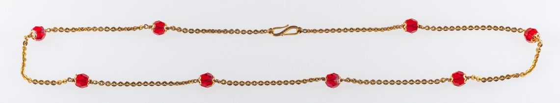 A 22ct gold necklace with faceted red glass beads,