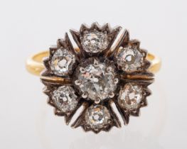 An antique dress ring, the flower head setting, with old cut diamonds set in silver with gold mount,