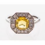 A plaque ring of octagonal form set with a yellow sapphire within a border of brilliant cut