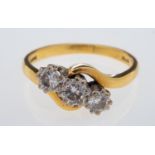 A three stone diamond ring, set with brilliant cut diamonds in crossover design mount, 18ct gold,