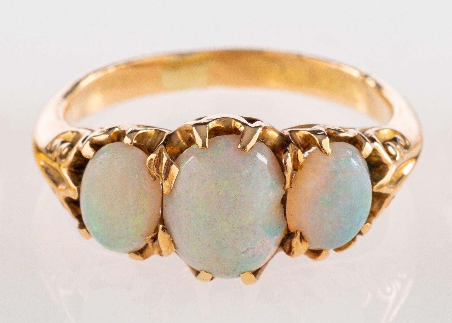 A three stone opal ring, set with three oval cabochon opals in claw settings, ring size O 1/2.