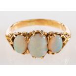 A three stone opal ring, set with three oval cabochon opals in claw settings, ring size O 1/2.